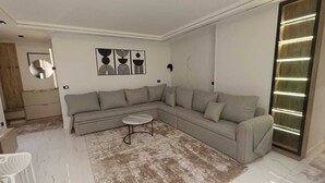 Un salon moderne avec un canapé d’angle gris, une petite table basse ronde et un tapis à motifs.