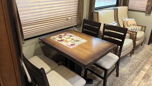 A cozy dining area with a wooden table, cushioned chairs, and a decorative placemat. - Cozy 1-bedroom caravan in lovely Aiken with AC (Aiken)