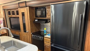 A compact kitchen with a stainless steel refrigerator, a microwave, a stove, and a sink. - Cozy 1-bedroom caravan in lovely Aiken with AC (Aiken)