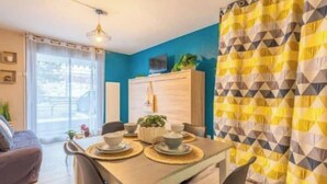 Un coin repas avec une table dressée pour deux personnes, un buffet et une vue par la fenêtre.