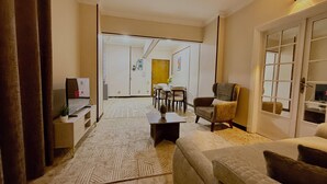 A living room with a sofa, armchair, coffee table, and TV. There is a dining area with chairs and a table in the background. - La Casa del Centro Cairo (Cairo)