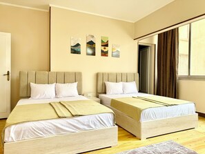 A hotel room with two beds, beige walls, and artwork on the wall. - La Casa del Centro Cairo (Cairo)