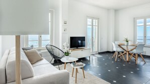 Una sala de estar moderna con un sofá, televisor, mesa de comedor y sillas.
