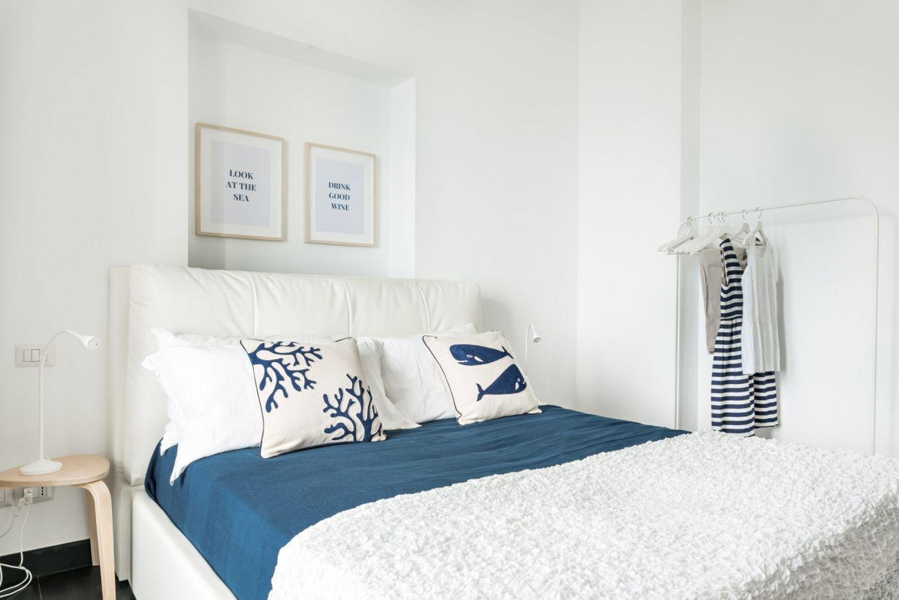 A neatly arranged bedroom with a bed, pillows, a bedside table, and a wall-mounted towel rack.
