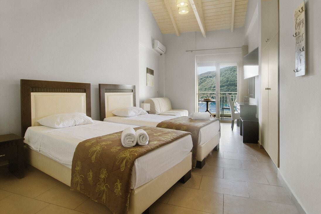 A hotel room with two beds, a balcony with a view, and a TV.