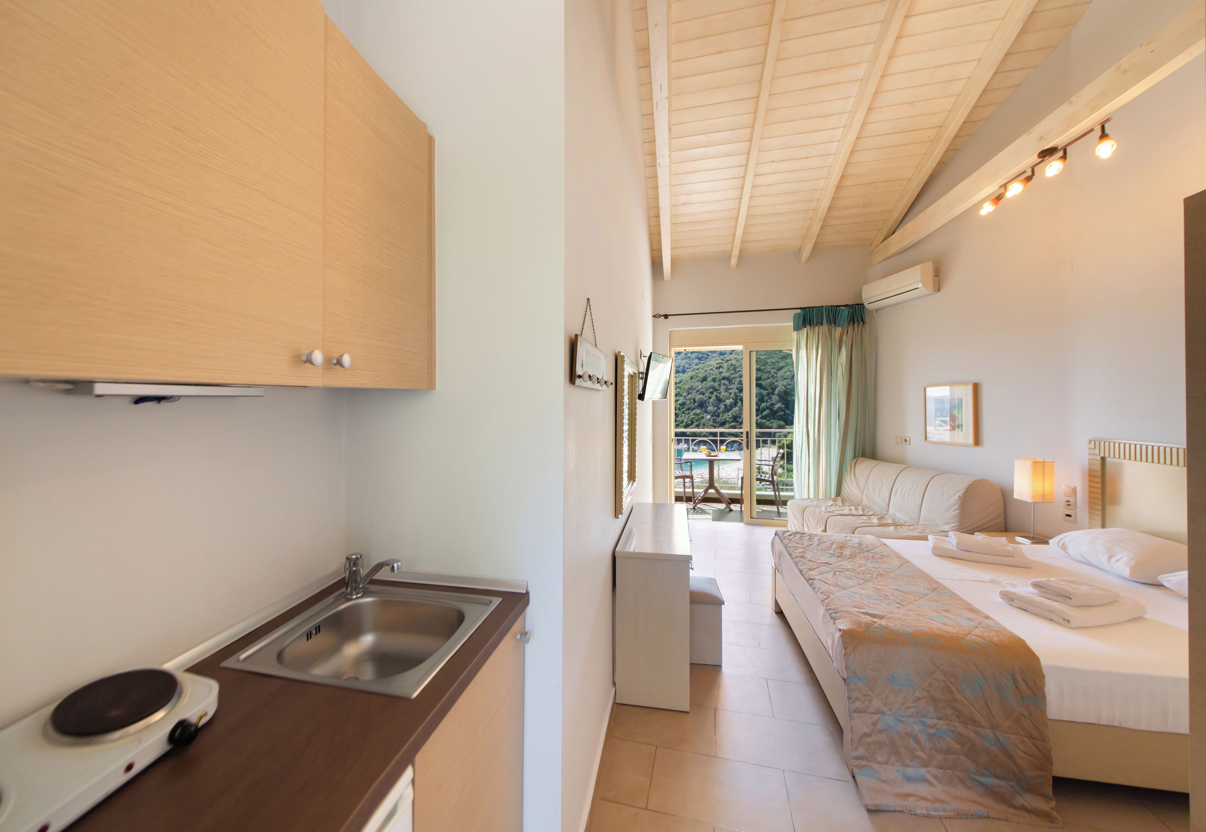Ein modernes Hotelzimmer mit Küchenzeile, einem Bett mit Blick und einem Essbereich.