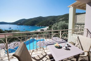A balcony with a pool, chairs, and a table with a plate of food and cups.