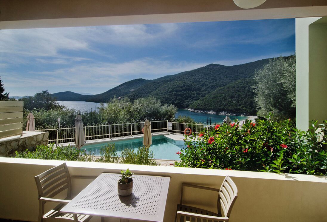 A terrace with a pool, outdoor seating, and a view of a lake and mountains.