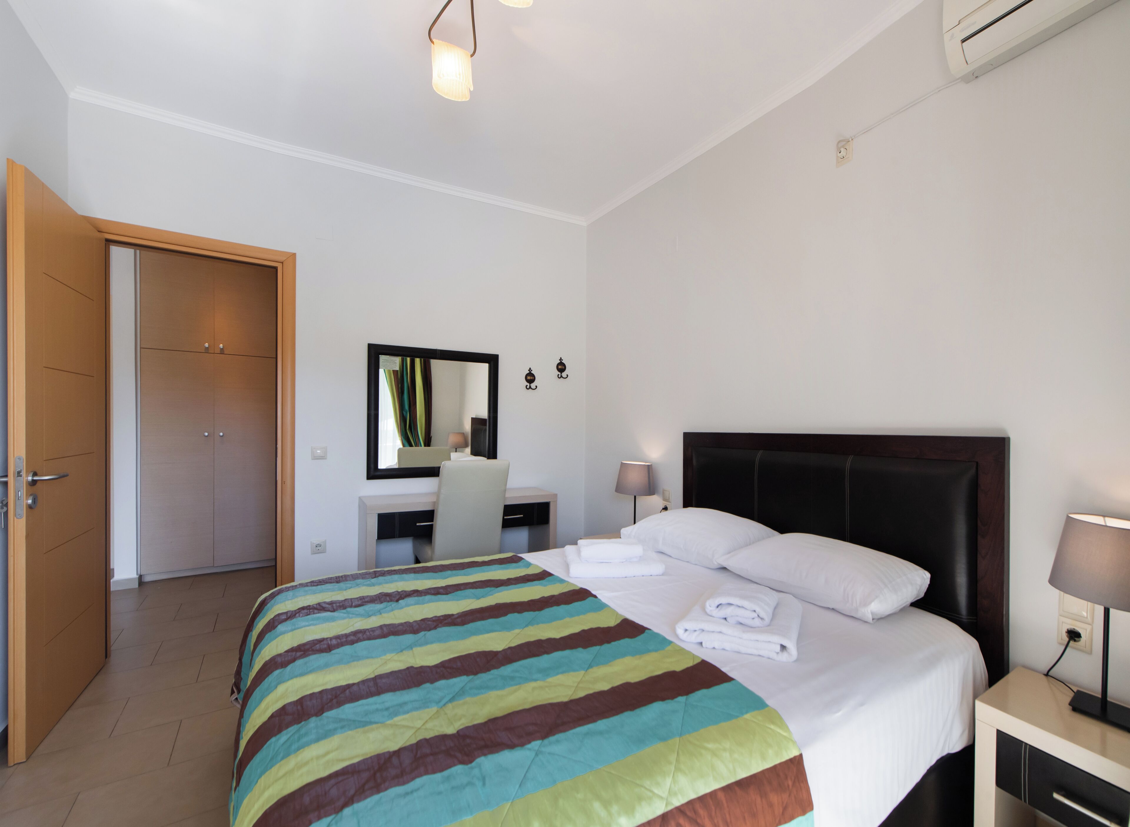 Una habitación de hotel con cama, mesita de noche, escritorio, silla y puerta.