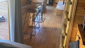 Ein Holzblockhaus-Innenraum mit Essbereich, einer kleinen Küche und einem Fenster mit Vorhängen.