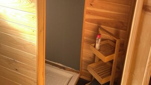 Ein Holzhütten-Innenraum mit kleinem Badezimmer, einem Spiegel und einem Ablagefach mit Toilettenartikeln.