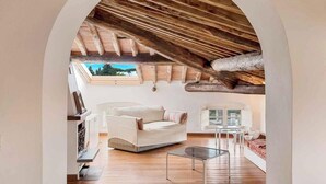 A cozy attic room with a wooden ceiling, a sofa, a glass table, and a view through a skylight. - ‘La Tuile’ in Lerici, a hidden gem that promises an unforgettable experience with breathtaking sea views. This exclusive penthouse, located in a privileged position, invites you to experience moments of pure relaxation and tranquillity in its idyllic (Lerici)