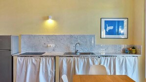Eine kleine Küche mit Spüle, Arbeitsfläche und Essbereich mit Tisch und Stühlen.