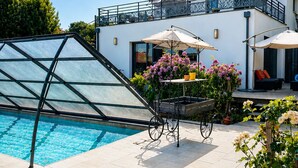 Une maison moderne dotée d’une piscine, d’un patio couvert et d’un jardin.