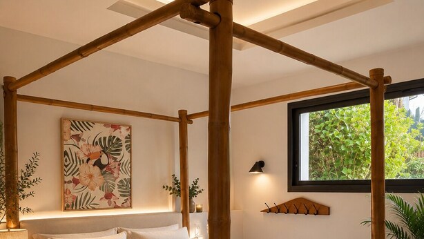 Une chambre à coucher moderne avec un lit à baldaquin, une grande fenêtre et une décoration murale sur le thème des tropiques.