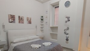 A modern bedroom with a large bed, white walls, and a small window. - Domus Tiziano: Elegant Living Room 30m from Metro C - Center of Rome (Roma)