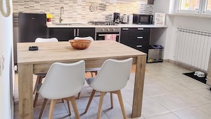 A modern kitchen with a central island, black cabinets, a microwave, and a gas stove. - Domus Tiziano: Elegant Living Room 30m from Metro C - Center of Rome (Roma)