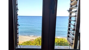 Ett fönster med utsikt över havet och stranden.