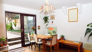 A dining area with a wooden table and chairs, a bench, and a hanging plant. - Artist house with garden sauna in London (London)