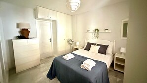 Et hotelværelse med seng, natbord, lampe, garderobeskab og loftlampe.