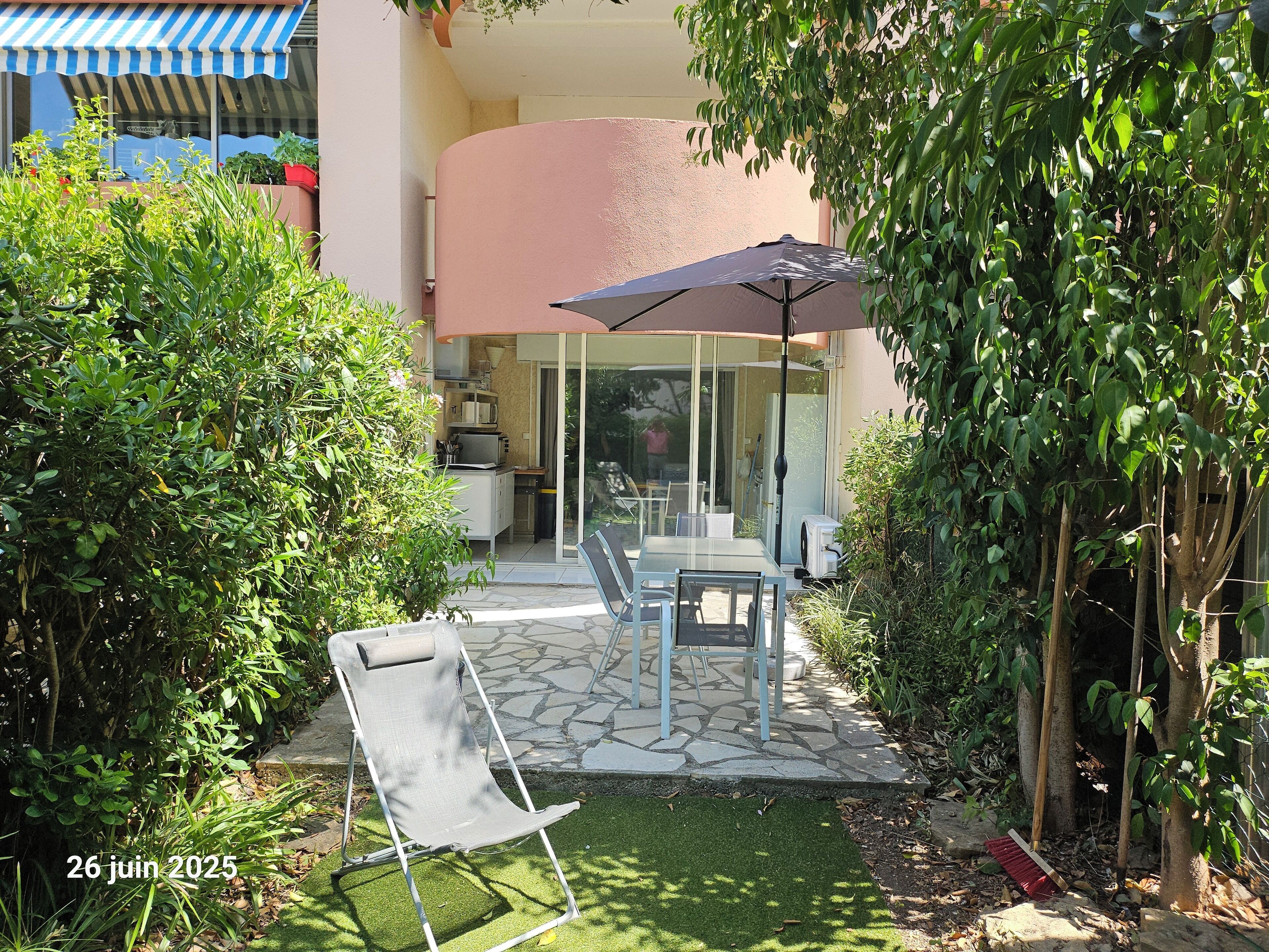 Eine Terrasse mit Tisch, Stühlen und einem großen Sonnenschirm.