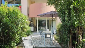 A patio area with a table and chairs, a folding chair, and a large umbrella. - 40m², 100m from beach, garden, 1 bedroom, living room (sofa bed), fiber box, air conditioning, no pets (La Ciotat)