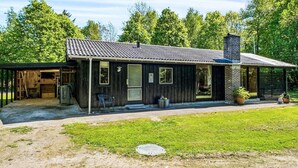 Une maison de plain-pied avec un garage, une véranda et une pelouse bien entretenue.