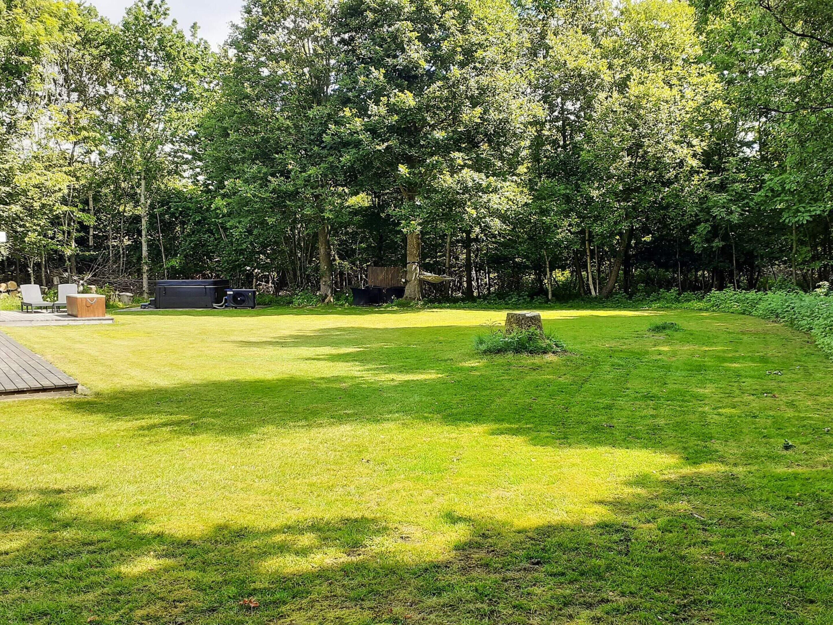 A well-maintained grassy yard with a wooden deck and outdoor furniture.