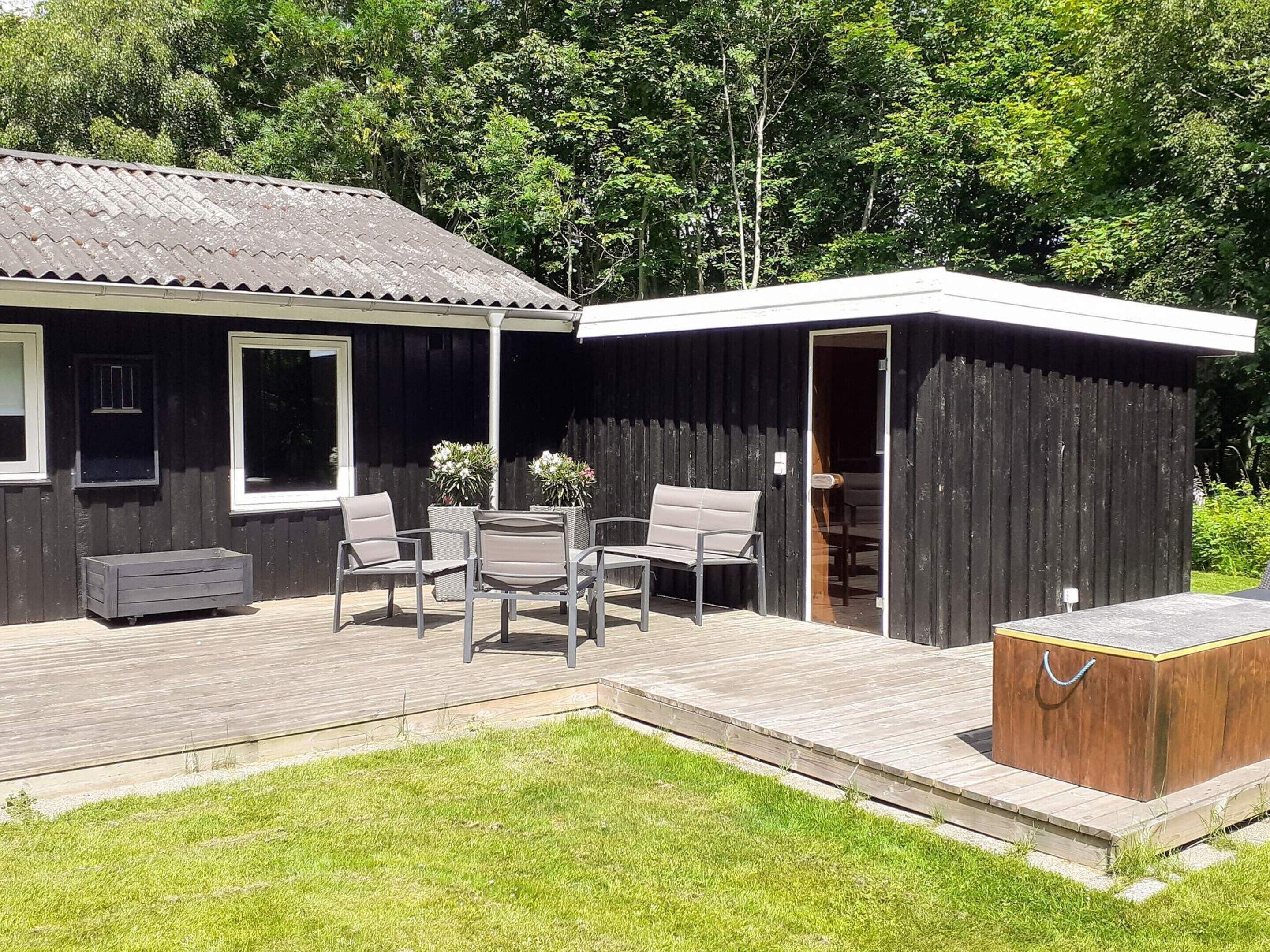 A wooden cabin with a patio, outdoor seating, and a small shed.