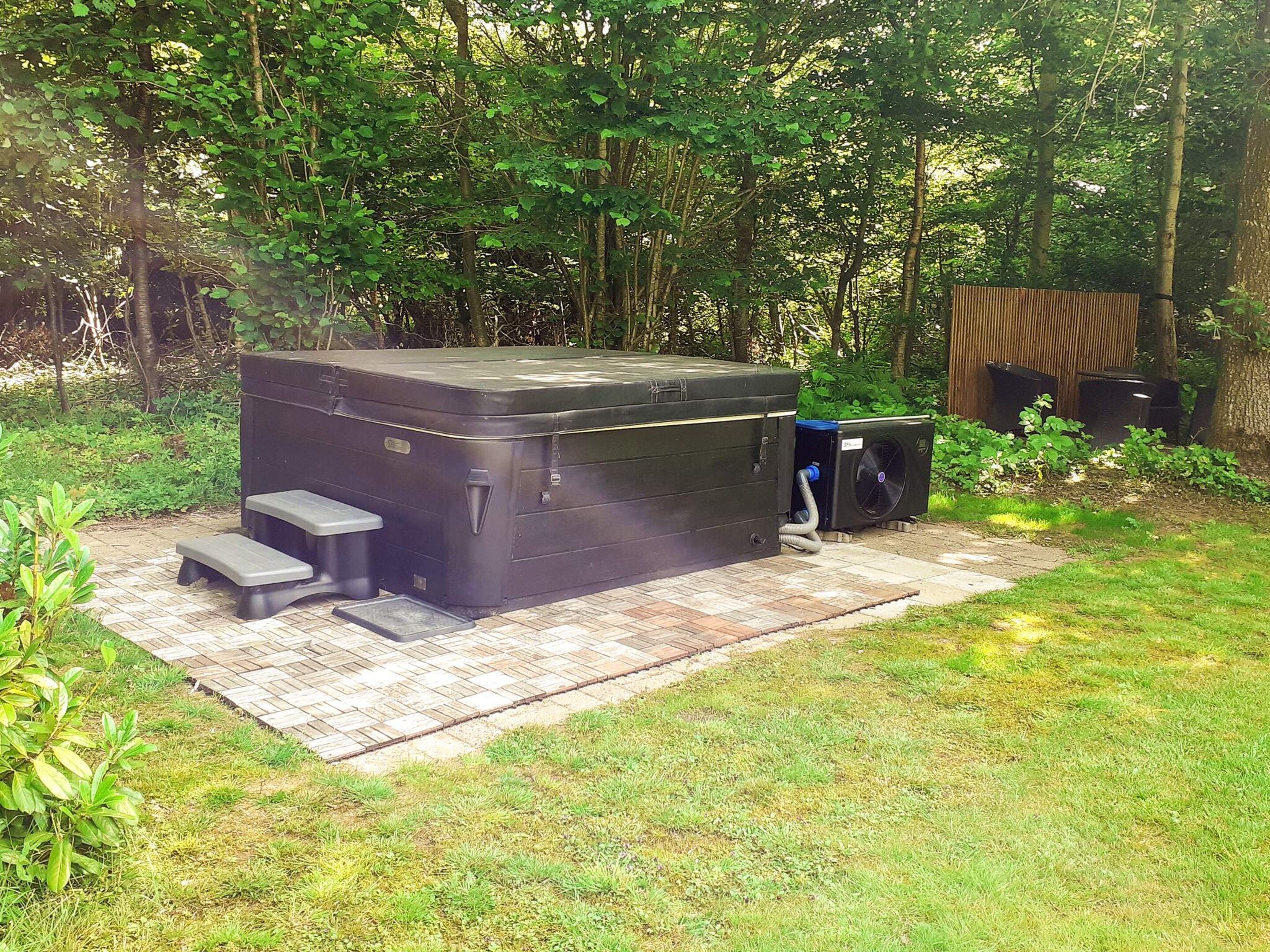 A hot tub with steps, surrounded by a grassy area and trees.
