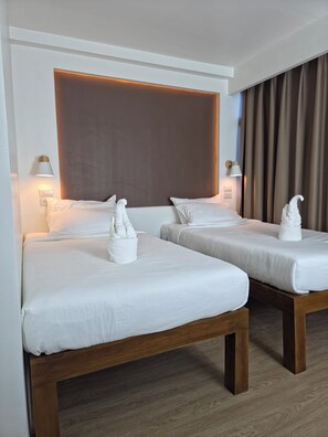 Una habitación de hotel con dos camas, cabecero de madera y lámparas de pared.
