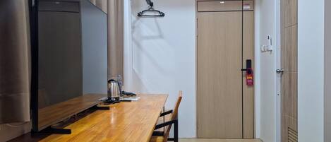 A modern room with a wooden table, chairs, a TV, and a door.