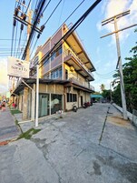 A multi-story hotel with balconies, a signboard, and a parking area.