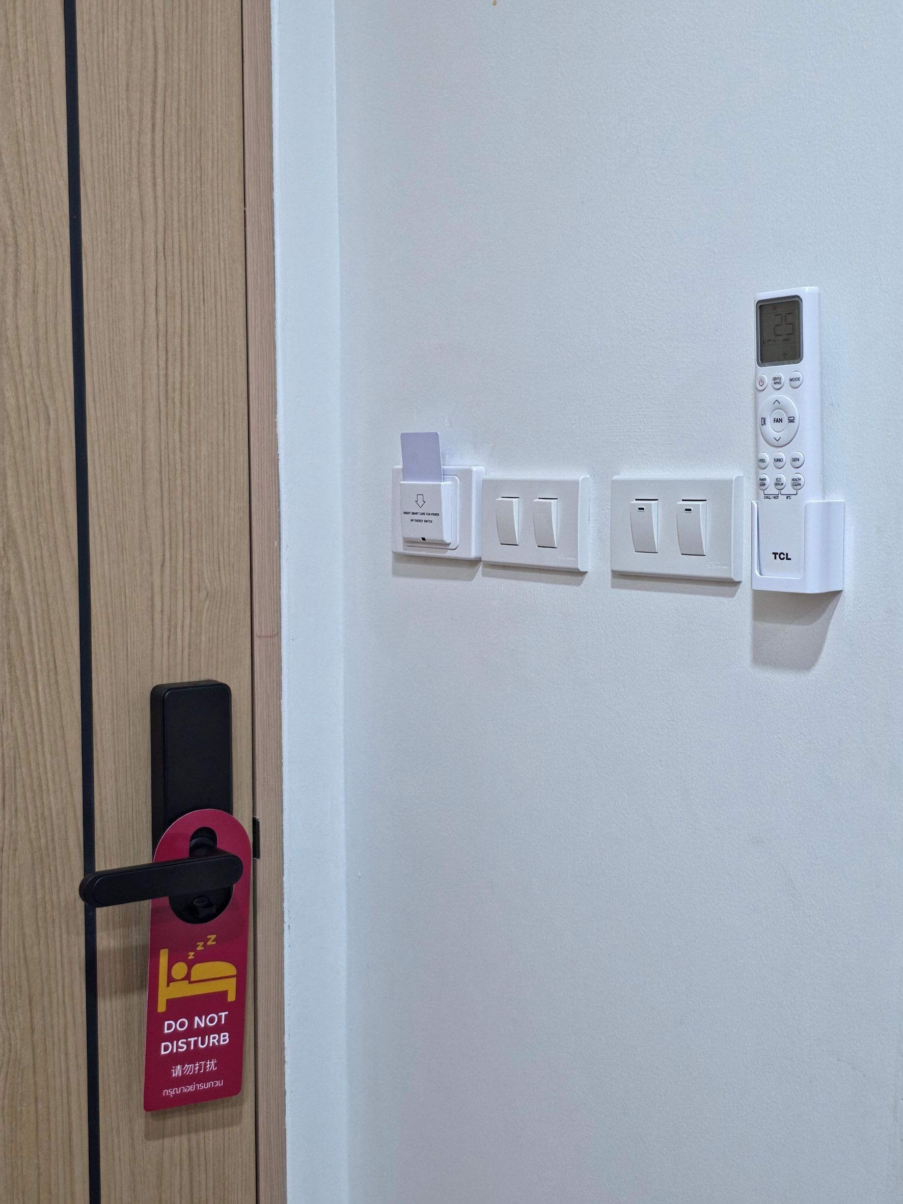 Une porte avec une pancarte indiquant « Ne pas déranger », un lecteur de carte magnétique, un thermostat numérique et une prise de courant.
