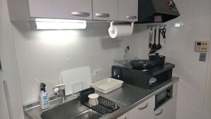A compact kitchen with a stainless steel sink, a black range hood, and a white countertop.