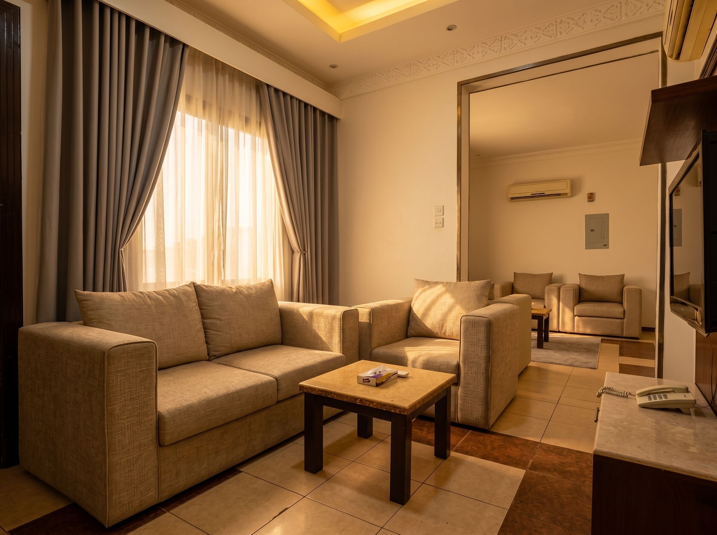 A living room with a sofa, armchairs, a coffee table, and a TV.