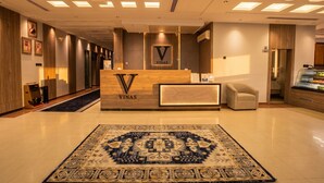 A hotel reception area with a reception desk, a carpeted floor, and a wall-mounted air conditioning unit. - Vinas Riyadh Serviced Apartments (Riyadh)