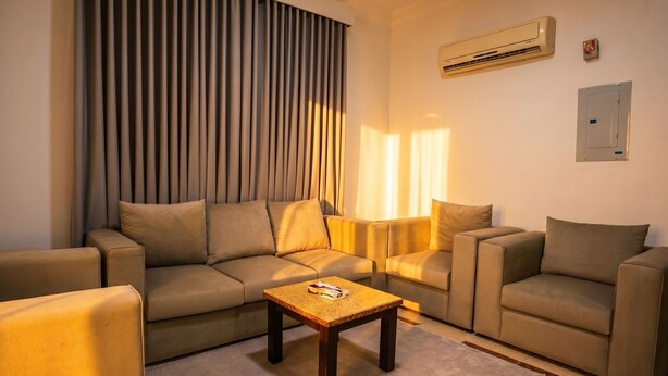 A living room with a sectional sofa, a coffee table, and a wall-mounted air conditioner. - Vinas Riyadh Serviced Apartments (Riyadh)