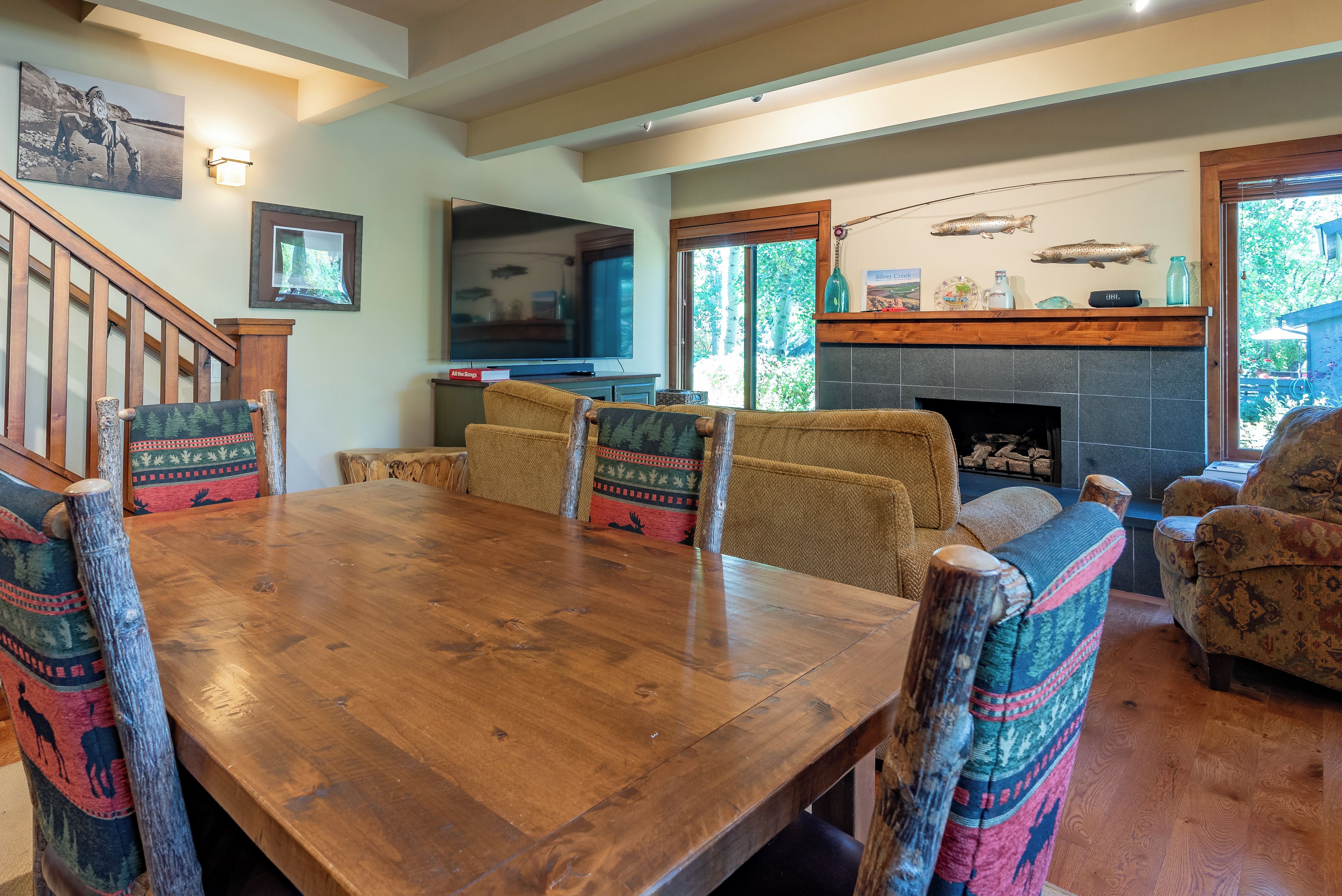 A spacious living room with a wooden dining table, comfortable seating, a fireplace, and a large TV.