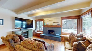Ein Wohnzimmer mit Kamin, Fernseher und gemusterten Sofas.