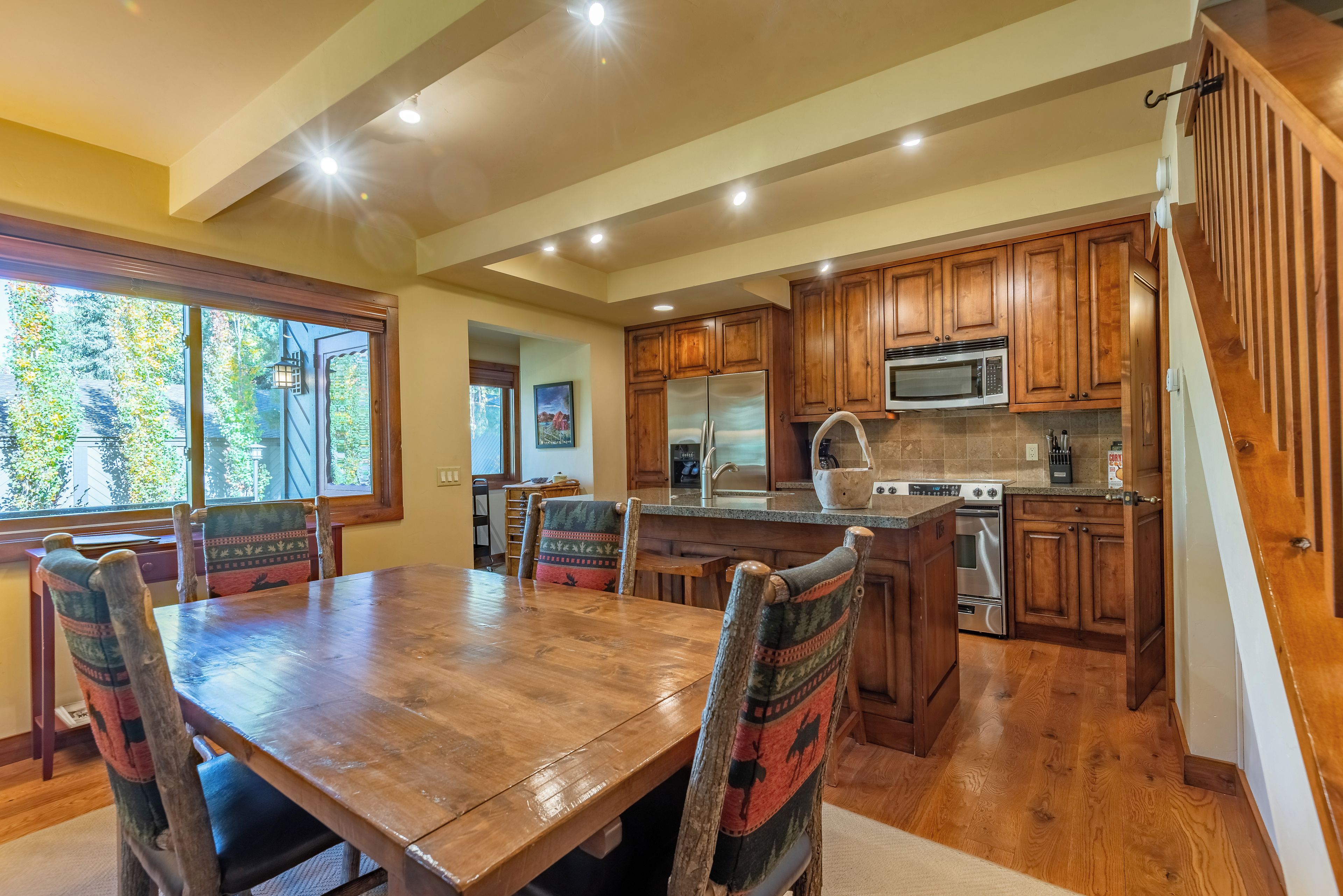 Una cocina amplia con armarios de madera, una isla grande y un comedor con mesa y sillas de madera.