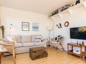 A cozy living room with a sofa, a coffee table, a TV, and a bookshelf.