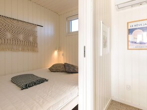 Un dormitorio con una cama, un tapiz de macramé, una ventana y un cartel en la pared.