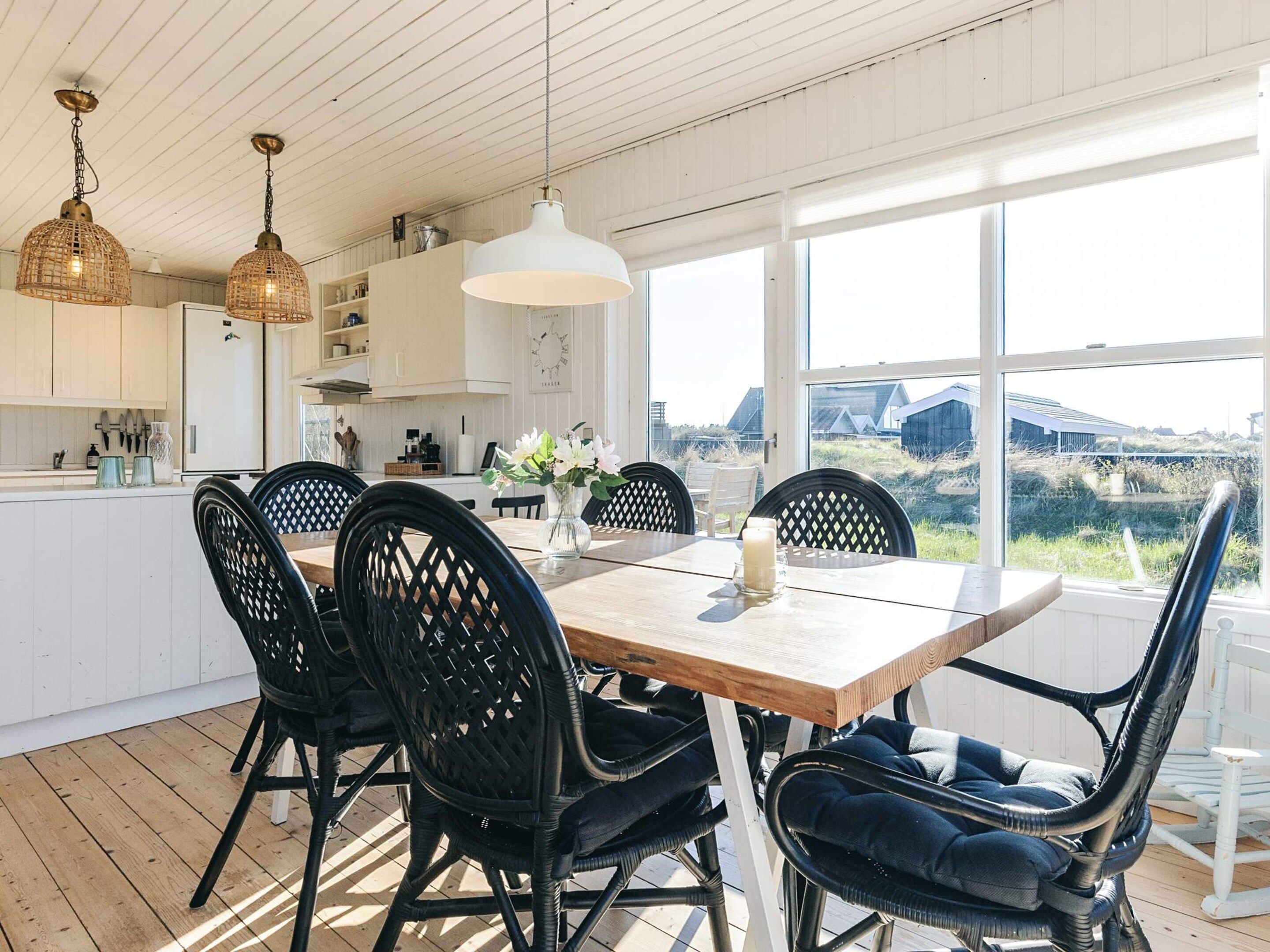 Una cocina moderna con armarios blancos, una mesa de comedor de madera y sillas negras.