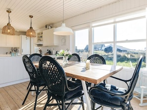 A modern kitchen with white cabinets, a wooden dining table, and black chairs. - 4 Star Holiday Home in Skagen (Skagen)