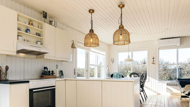 Una cocina moderna con armarios blancos, una isla central e iluminación colgante.