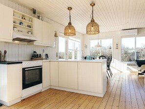 Una cocina moderna con armarios blancos, una isla central e iluminación colgante.