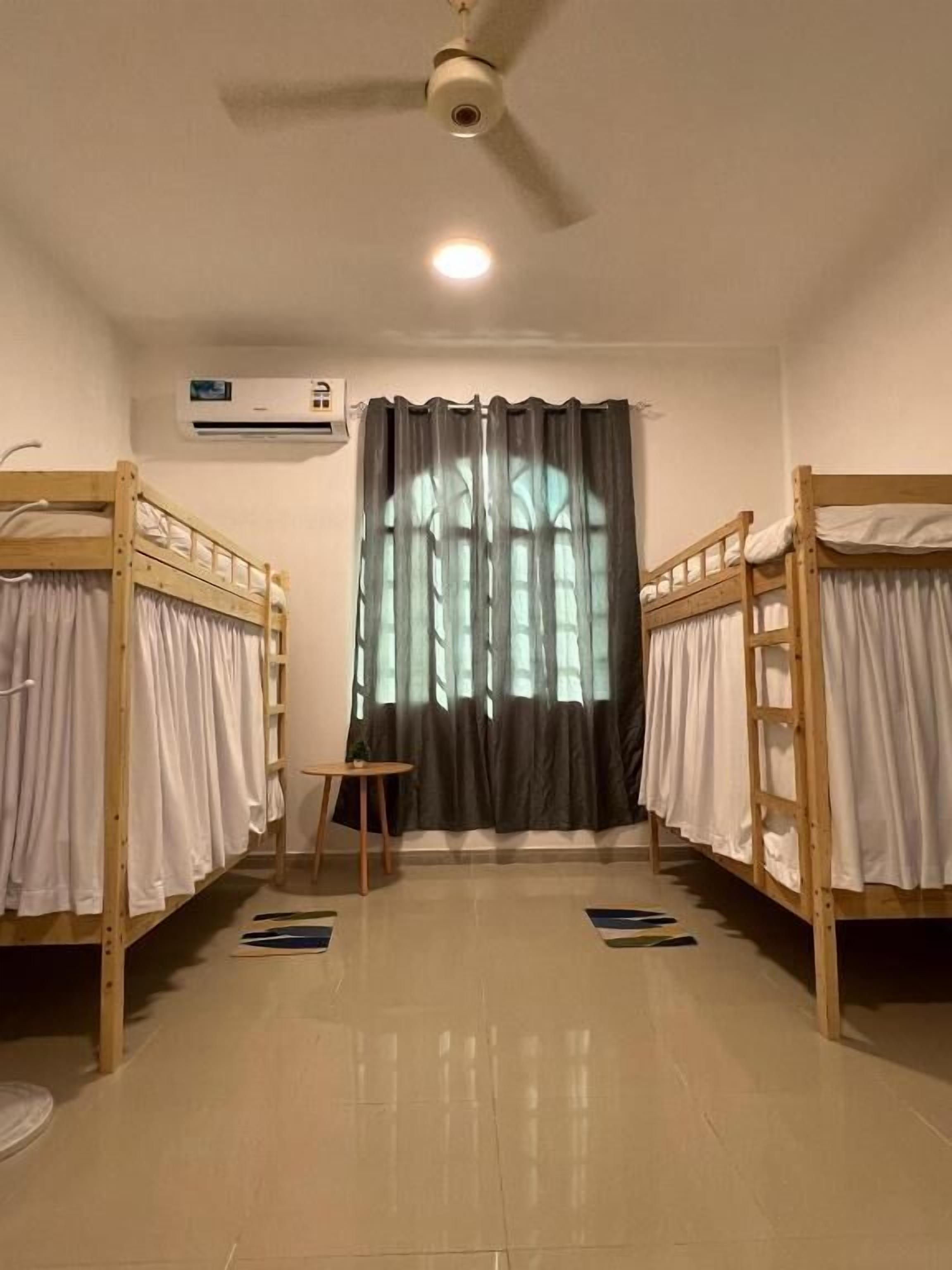 Un dormitorio con literas, ventilador de techo, aire acondicionado y ventana con cortinas.