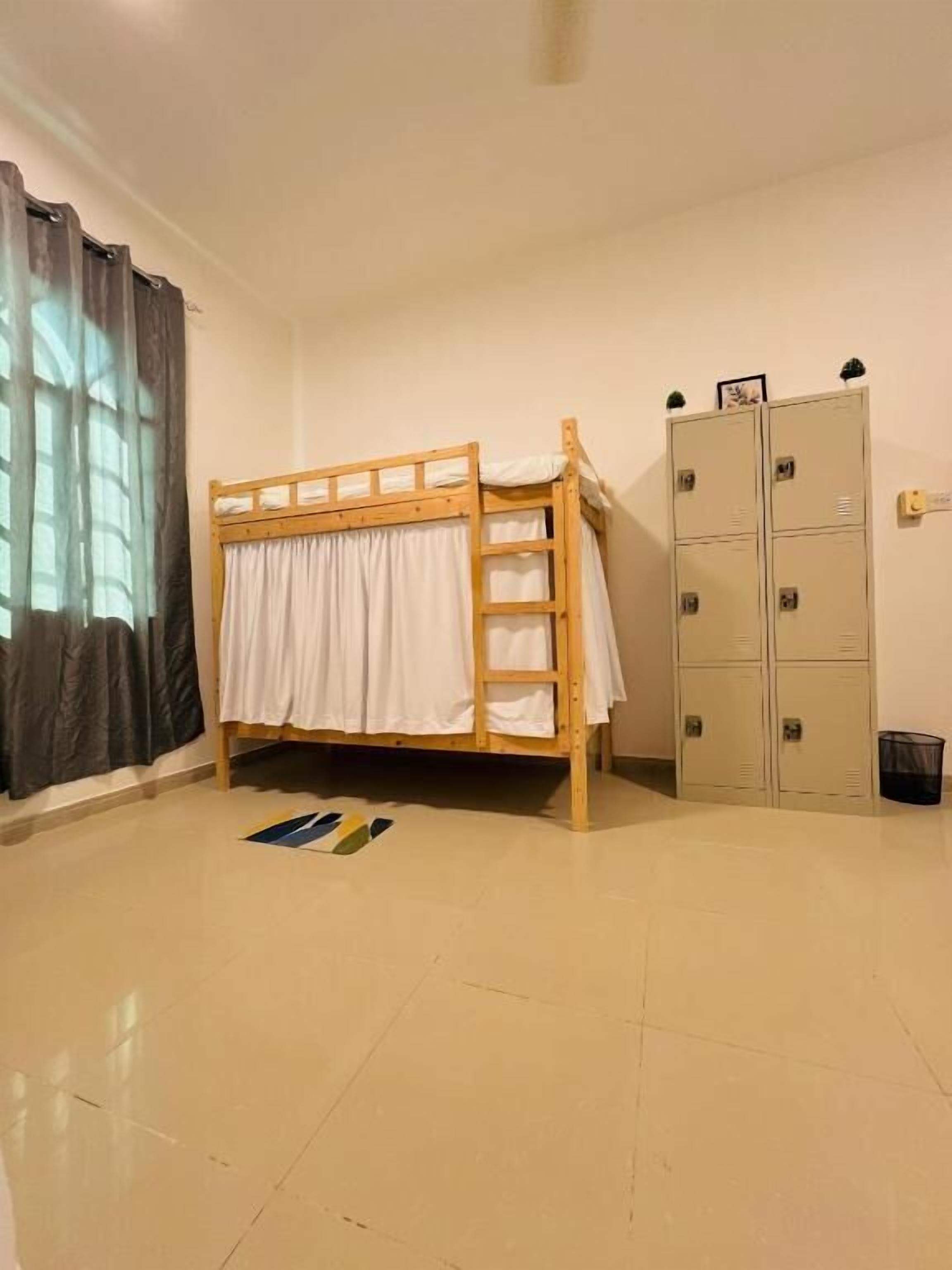 Una habitación con literas, taquillas y una ventana con cortinas.