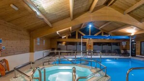 An indoor swimming pool with a glass-enclosed hot tub, wooden beams, and lounge chairs. - Swanmere lodge, lakeside view cabin at Pinelake Carnforth (Carnforth)